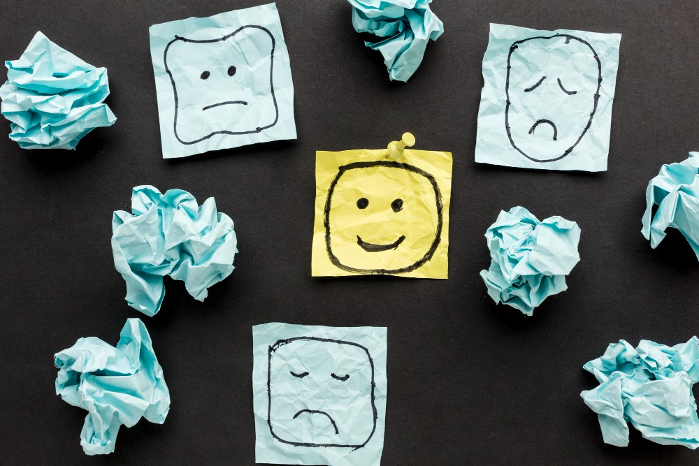 Post-its con caras tristes y una feliz en el centro, simbolizando cómo transformar pensamientos negativos en un motor para el cambio